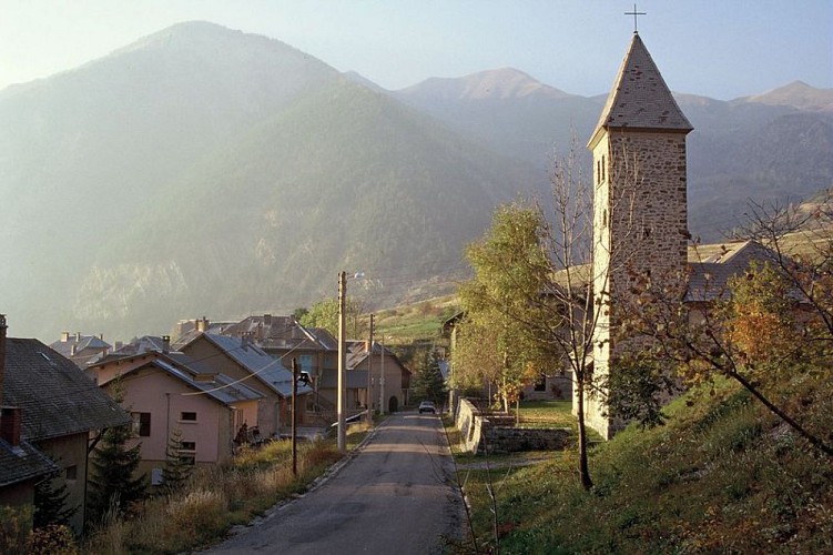 Le petit village de Meyronnes en chaude lumière rasante de fin de journée et en léger contre-jour, le clocher de l'église