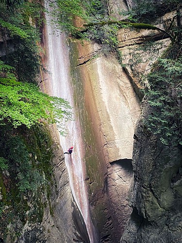 Un canyoniste descend la cascade en rappel