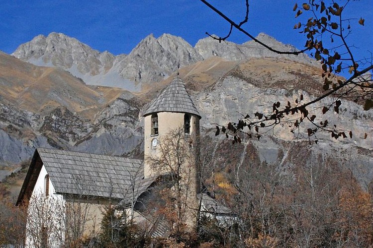 L'église d'Entraunes avec sa toiture de clocher dissymétrique, et l'ensemble de ses toits en bardeaux de mélèzes. Photographié e