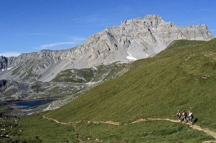Groupe de randonneurs sur un sentier. Vue sur le Lac Merlet inférieur (en bas, à g.) et l'Aiguille du Fruit (au fd., à dr.).
