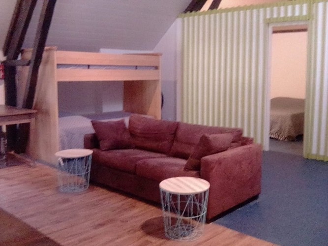 Un deuxième salon avec canapé convertible et en arrière-plan deux lits superposé