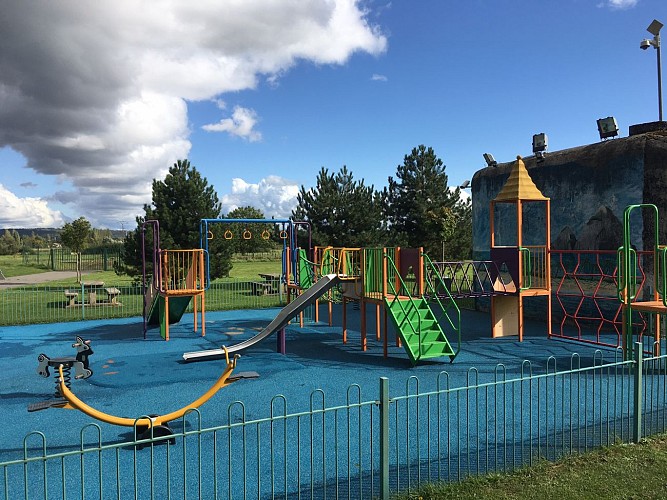 Table de pique-nique à proximité d'une aire de jeux pour enfants et d'un city stade