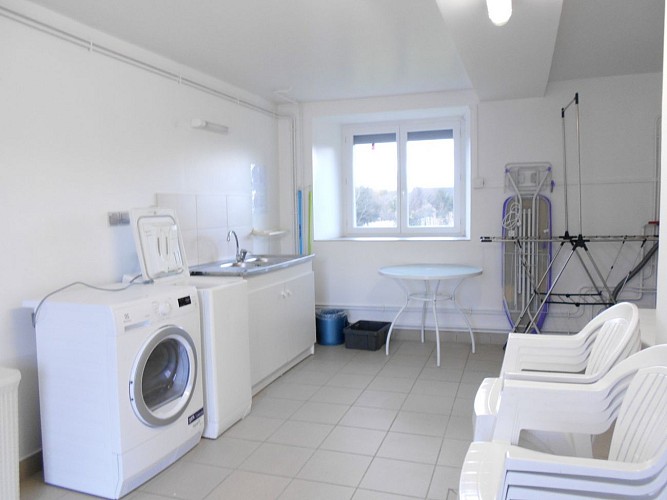 Buanderie avec lave linge,sèche linge, table et chaises d'extérieur. RdC