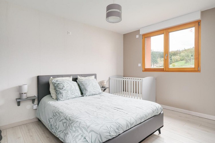 Chambre avec un lit double et un lit bébé.