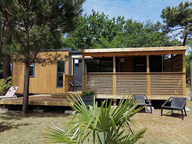 mobil-home-PRESTIGE-grand-confort-6-personnes-camping-les-ourmes-vue-exterieure-avec-4-fauteuils-de-jardin-et-2-bains-de-soleil