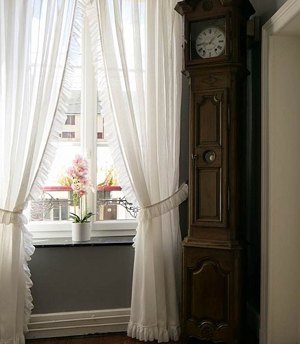 Couloir donnant sur une fenêtre et une horloge comptoise