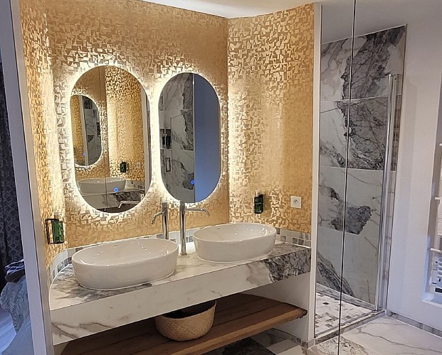 salle de bain avec double vasques et miroirs rétro éclairés.