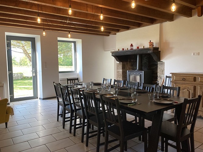 Pièce de vie (table 12 couverts, cuisine ouverte, poele à bois, 2 fauteuil)