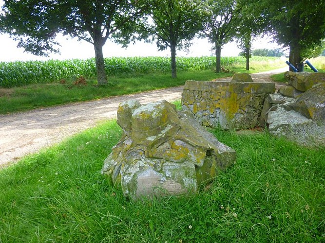 Les vestiges du monument originel. On peut distinguer les coiffes militaires rappelant les conflits.