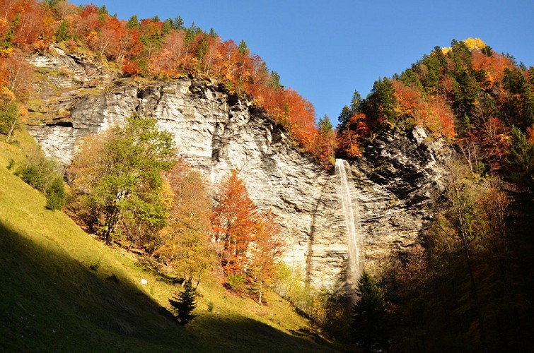 The Dard waterfall plunges down a cliff face, surround by trees in their autumn colours