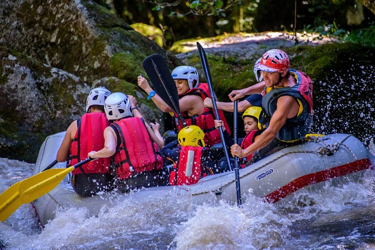 Rafting en famille : les enfants en sécurité à l'arrière du raft avec le guide.