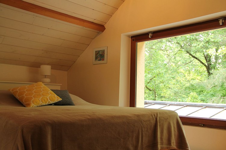 La chambre en mezzanine avec vue dans les bois